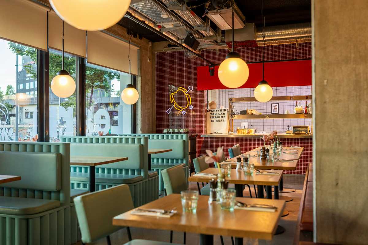 Scorcio di un tavolo apparecchiato all’aperto con piatti tipici di pesce, sullo sfondo il porto di Favignana e pescherecci locali